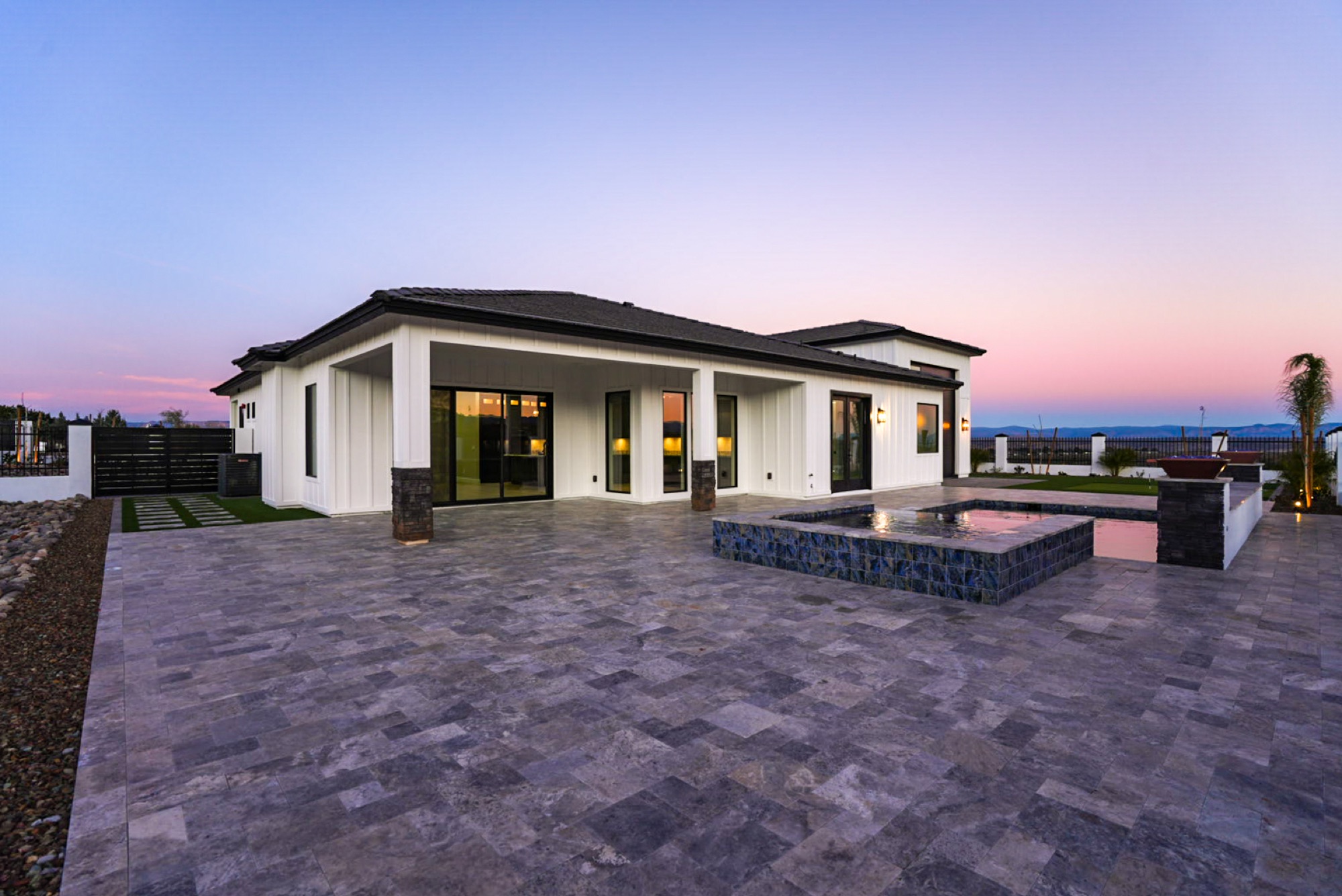 Wide view of the home, pool and spa at dusk