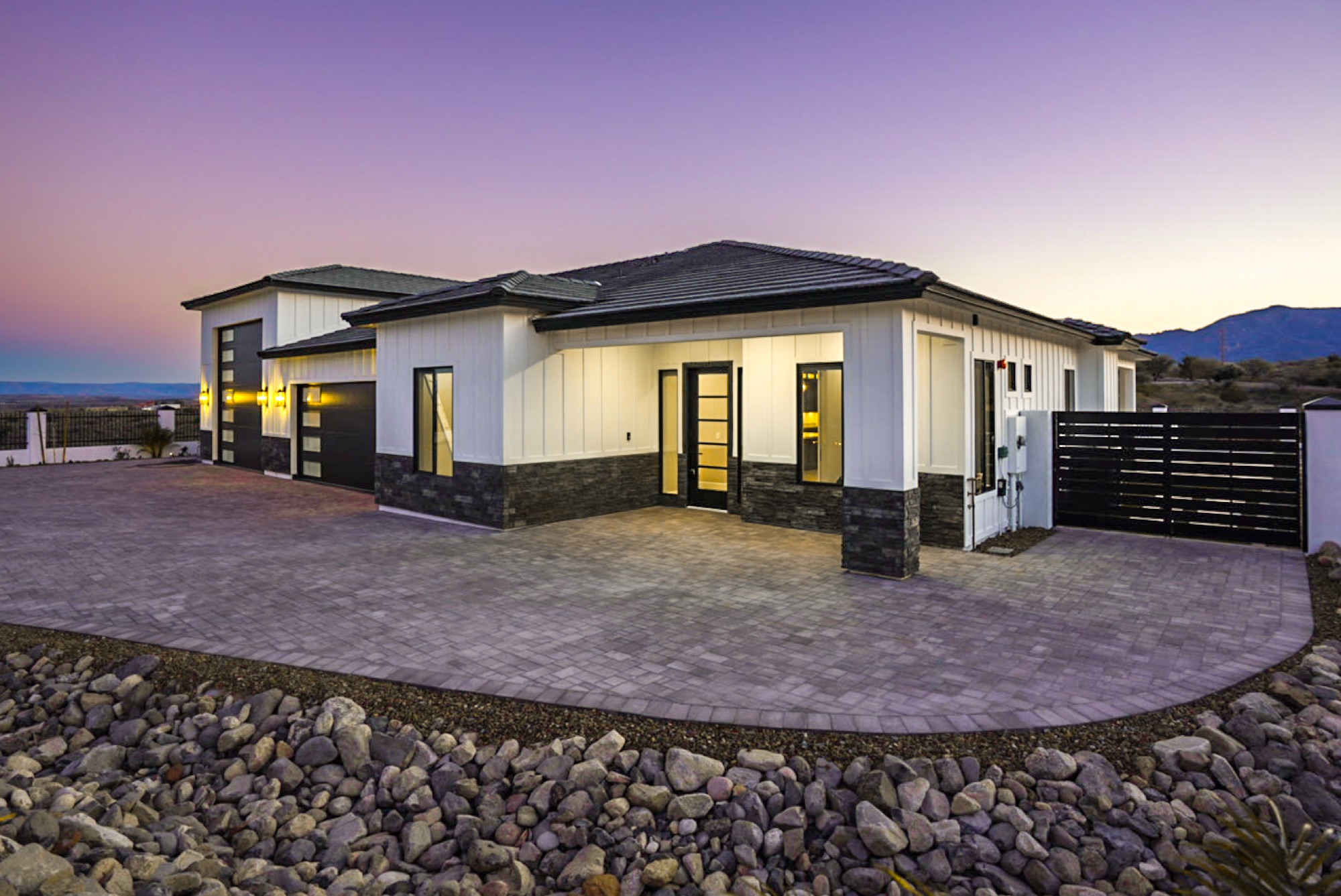 Front elevation at dusk with board-and-batten siding and stone