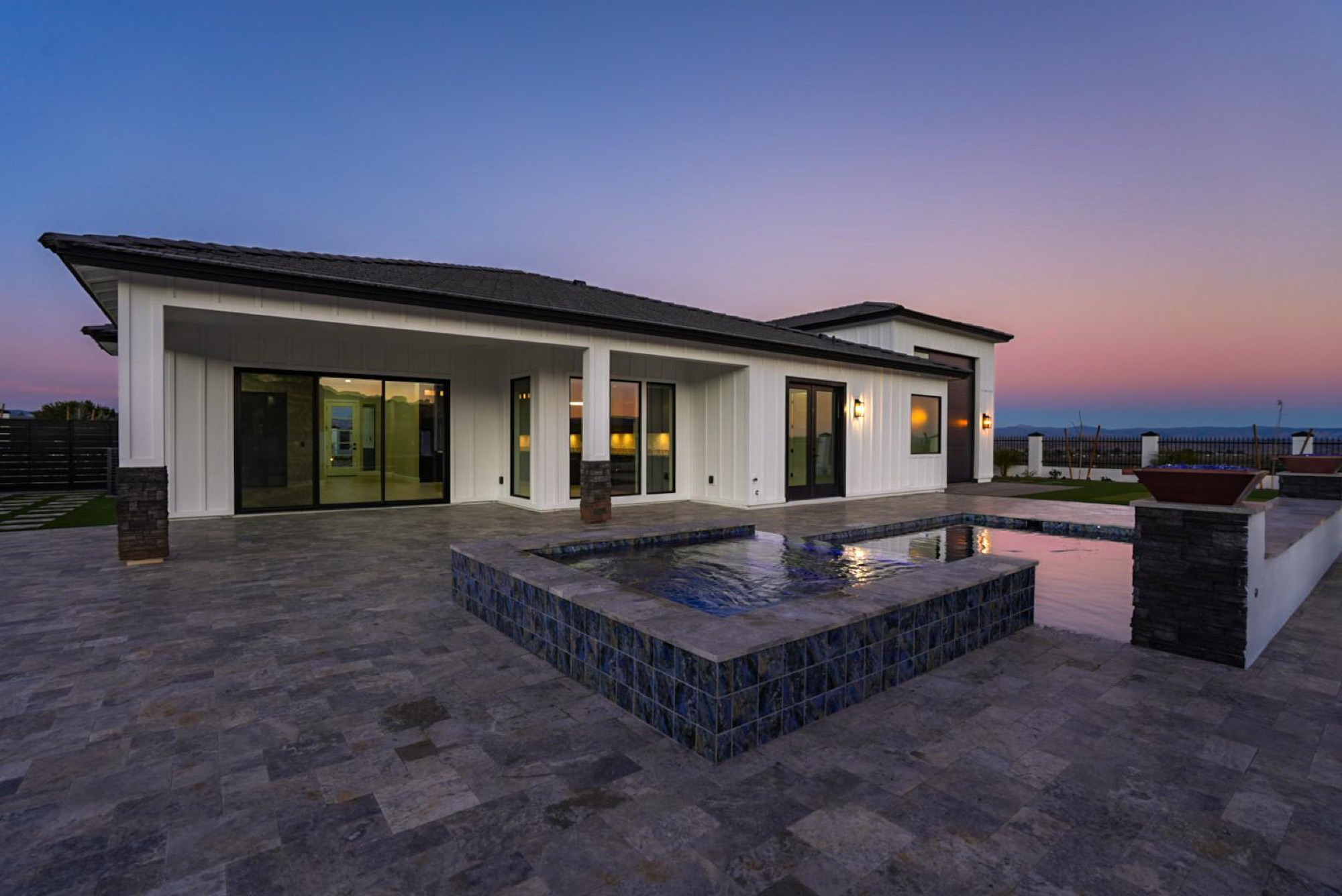 The home and pool at dusk with interior lights on