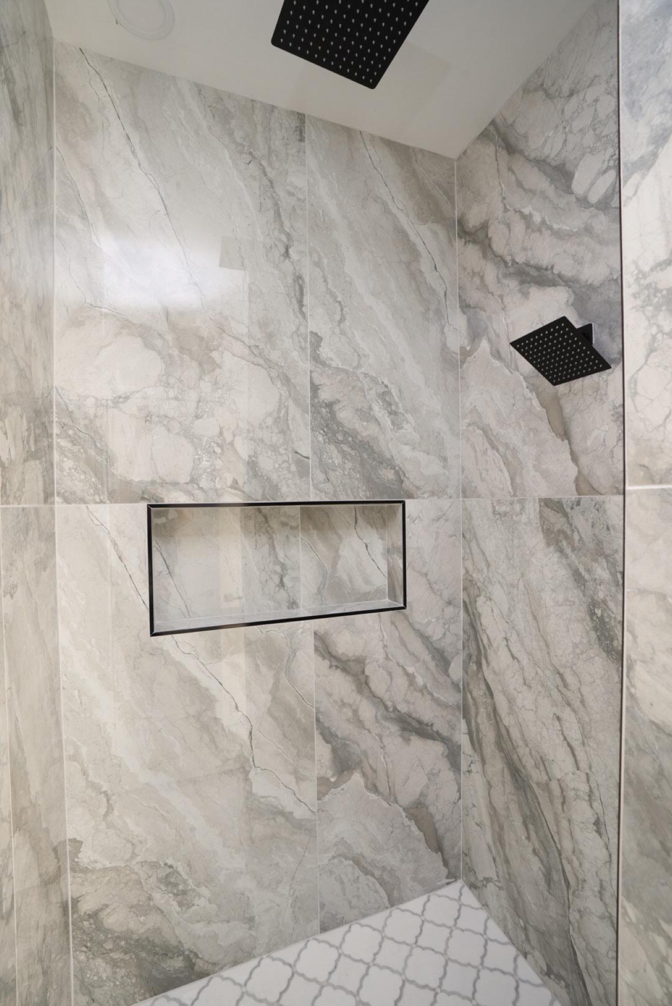 Marble-tiled shower with recessed niche and rain head